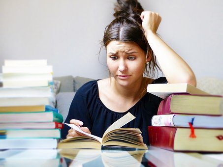 homework and stress girl reading pile of books studying